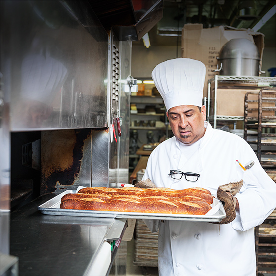 baker removes freshly baked bread from oven